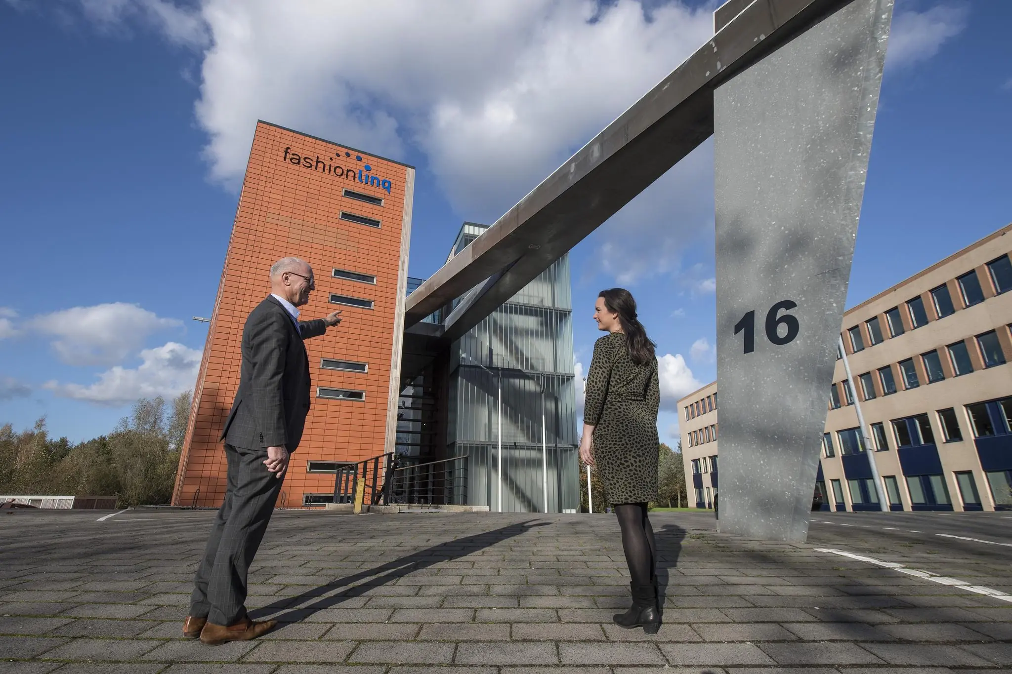 Twee mensen staan voor het gebouw van Fashion Linq aan de Fokkerstraat 16 en voeren een gesprek.
