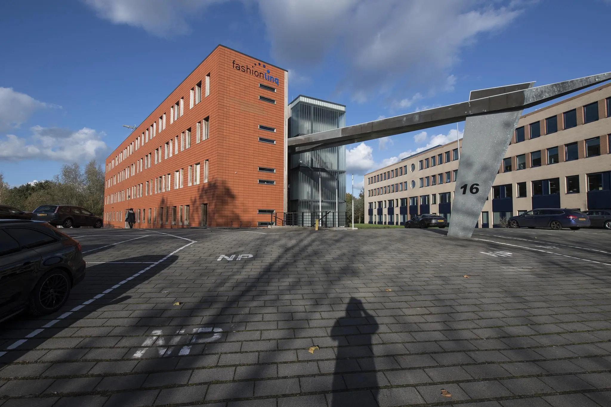 Kantoorpand van fashionlinq aan de Fokkerstraat met opvallende rode gevel en moderne loopbrug naar gebouw 16.