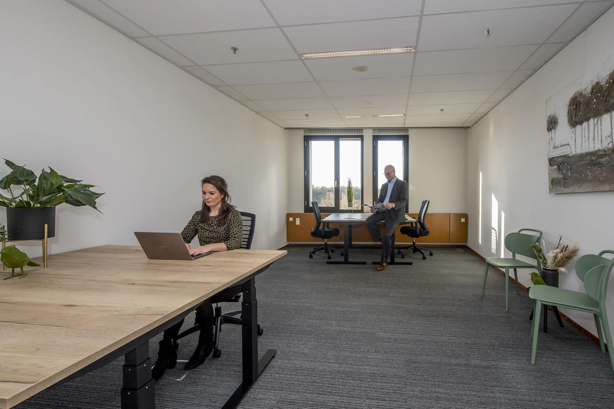 Twee mensen werken in een modern en licht kantoor aan de Fokkerstraat, met grote ramen en een minimalistische inrichting.