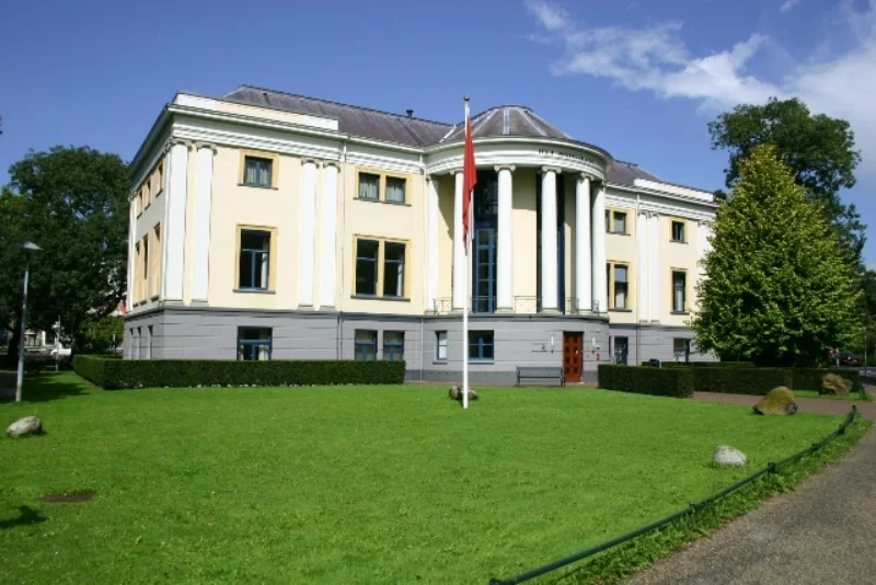 Een klassiek vormgegeven museumgebouw aan de Museumlaan, omringd door een groen gazon en blauwe lucht.