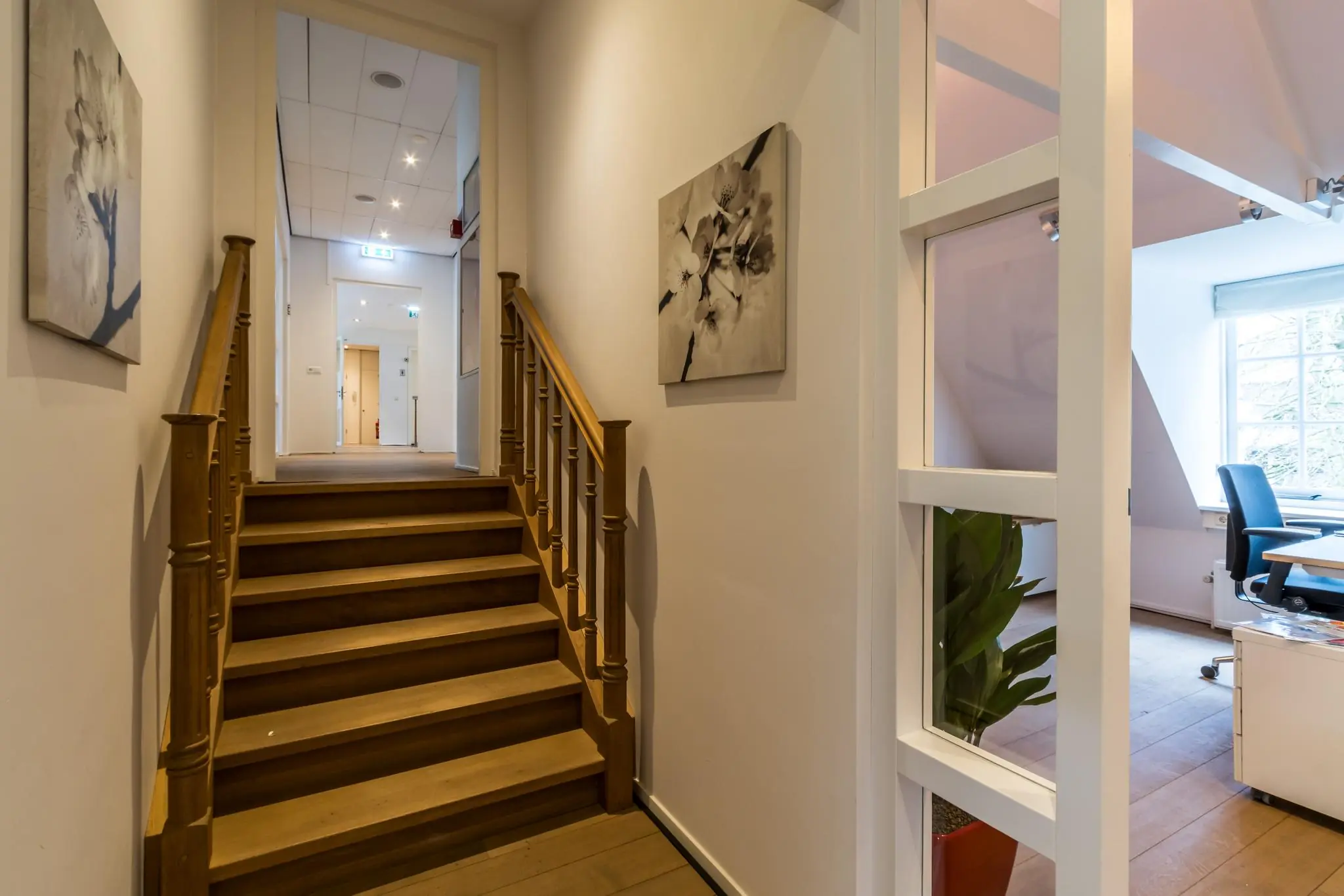Gang met houten trap en zicht op een kantoorruimte aan de Driebergseweg.