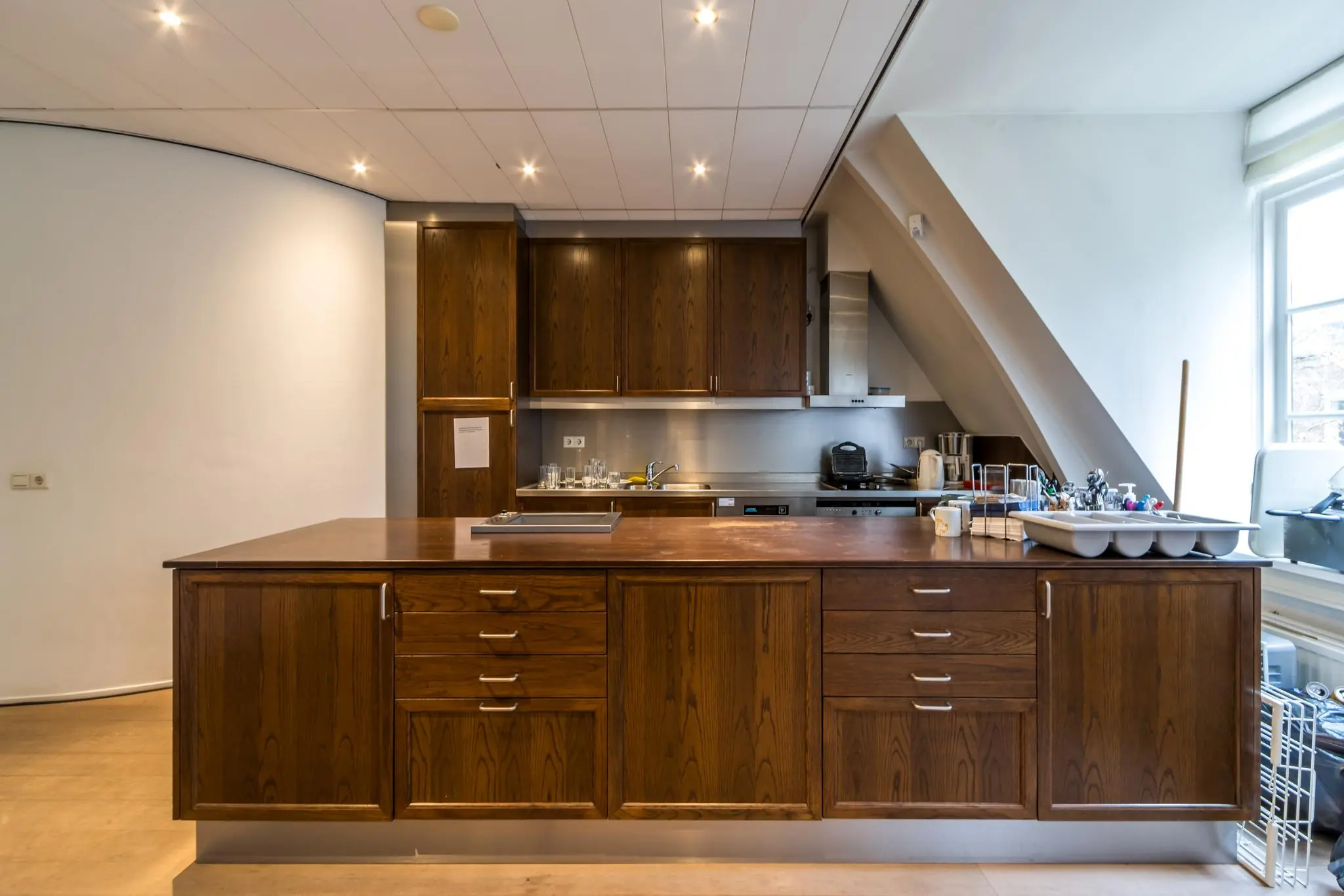 Moderne keuken aan de Driebergseweg met donkerhouten kastjes, rvs-afwerking en een kookeiland met spoelbak.