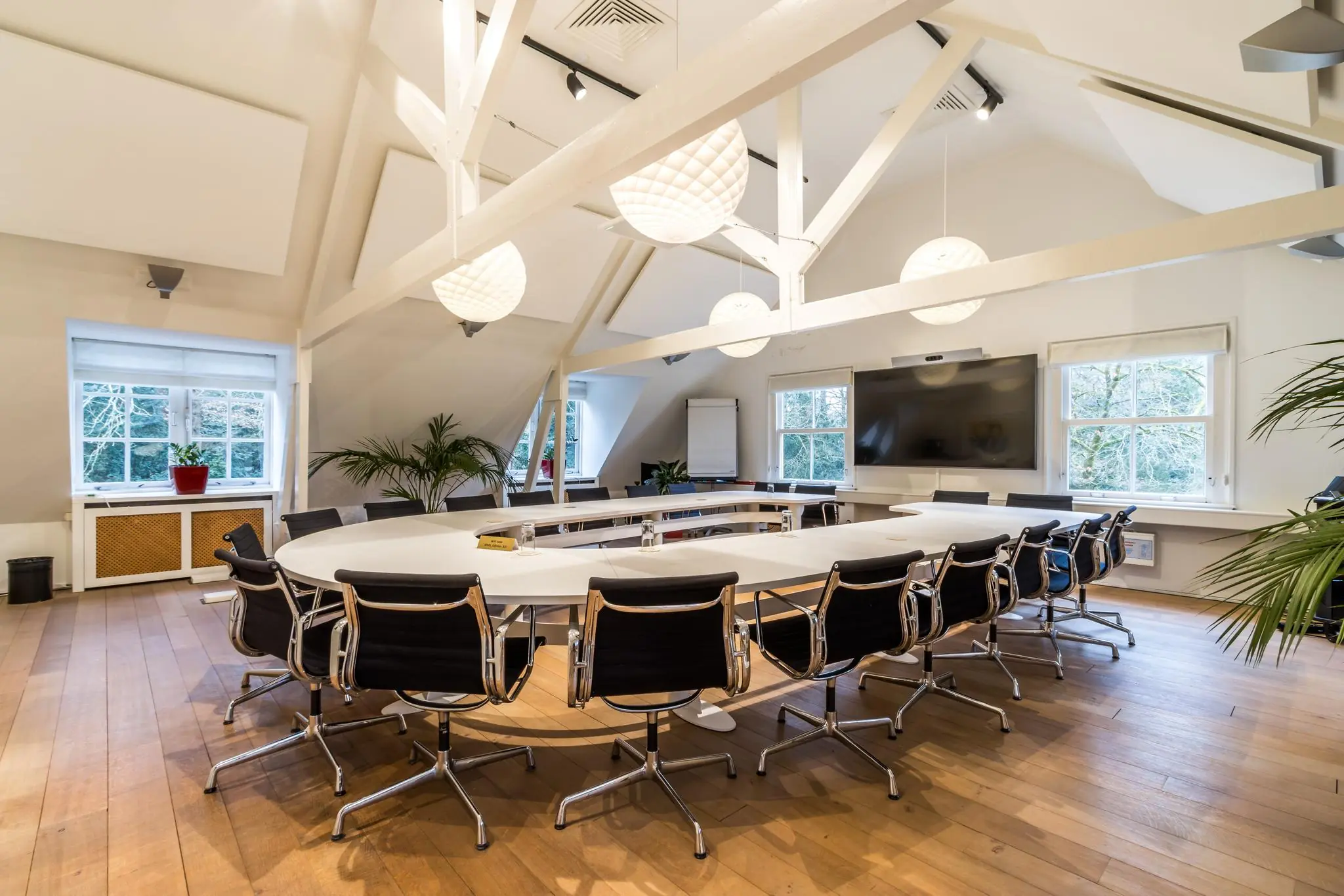 Moderne vergaderruimte aan de Driebergseweg met een ovaal gevormde tafel, luxe stoelen, groot presentatiescherm en veel natuurlijk licht.