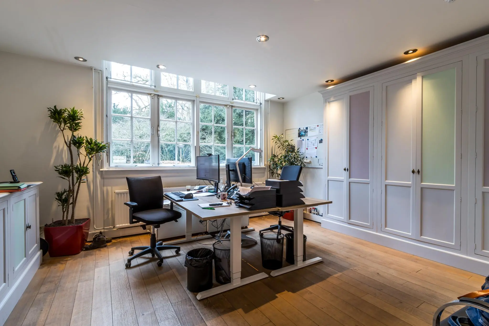 Modern en licht kantoor aan de Driebergseweg met houten vloer, grote ramen en opgeruimd bureau met twee werkplekken.