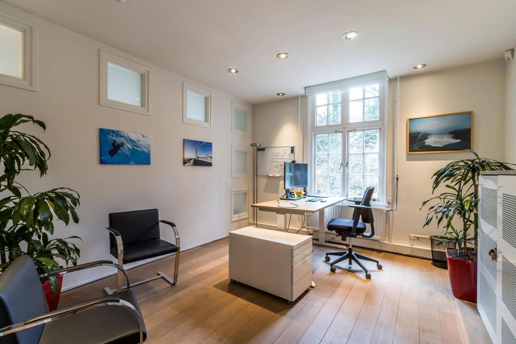 Modern ingerichte kantoorruimte aan de Driebergseweg met houten vloer, bureau bij raam en strak vormgegeven zitgedeelte.