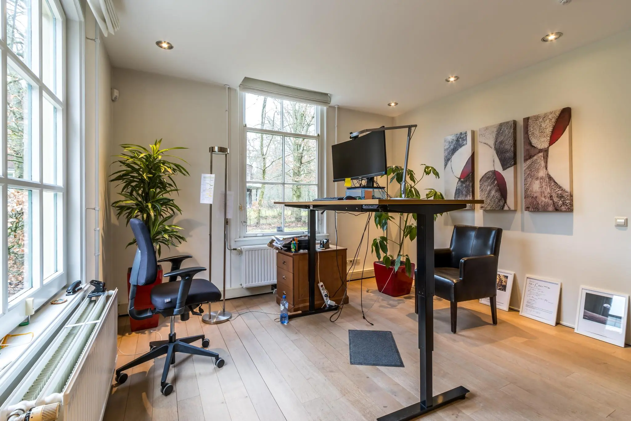 Modern thuiskantoor aan de Driebergseweg met een zit-sta bureau, ergonomische stoel en grote ramen met uitzicht op groen.