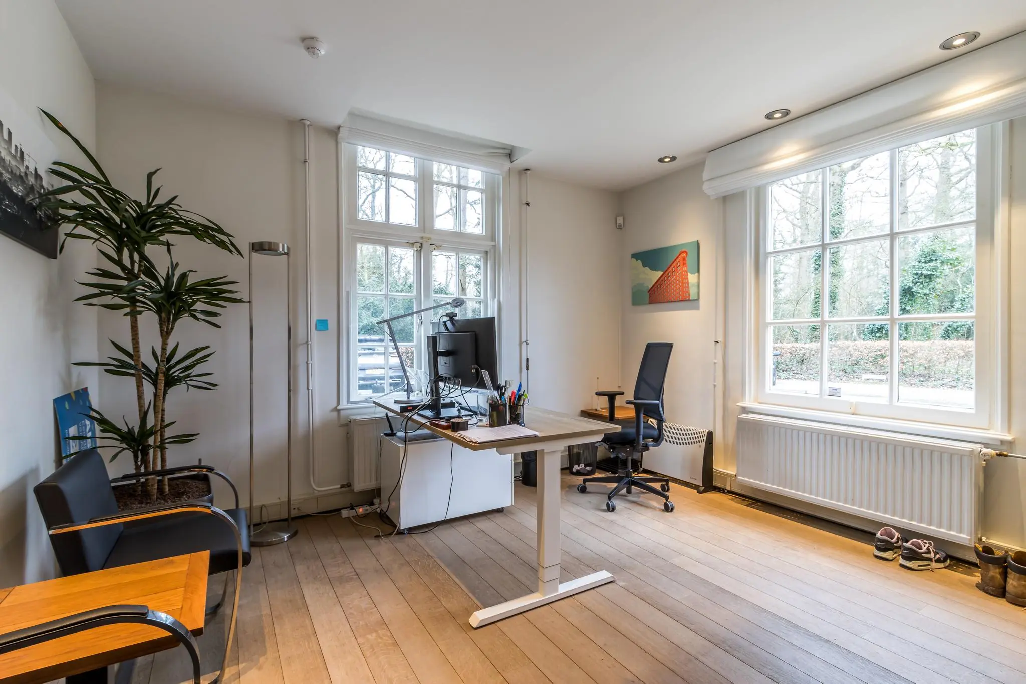 Modern ingericht thuiskantoor aan de Driebergseweg met bureau, bureaustoel en grote ramen met uitzicht op groen.