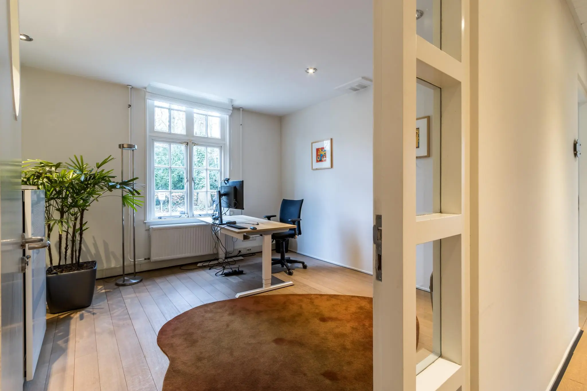 Modern ingericht thuiskantoor aan de Driebergseweg met groot raam, bureau, bureaustoel en kamerplant.
