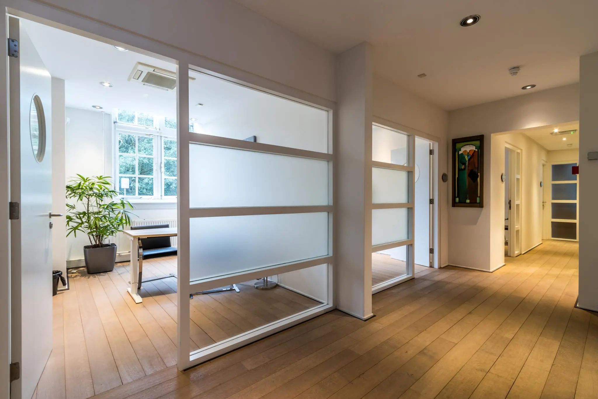 Lichte en moderne kantoorruimte aan de Driebergseweg met glazen wanden en houten vloer.