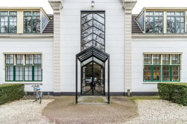 Moderne entree met glazen overkapping van een wit kantoorpand aan de Driebergseweg.