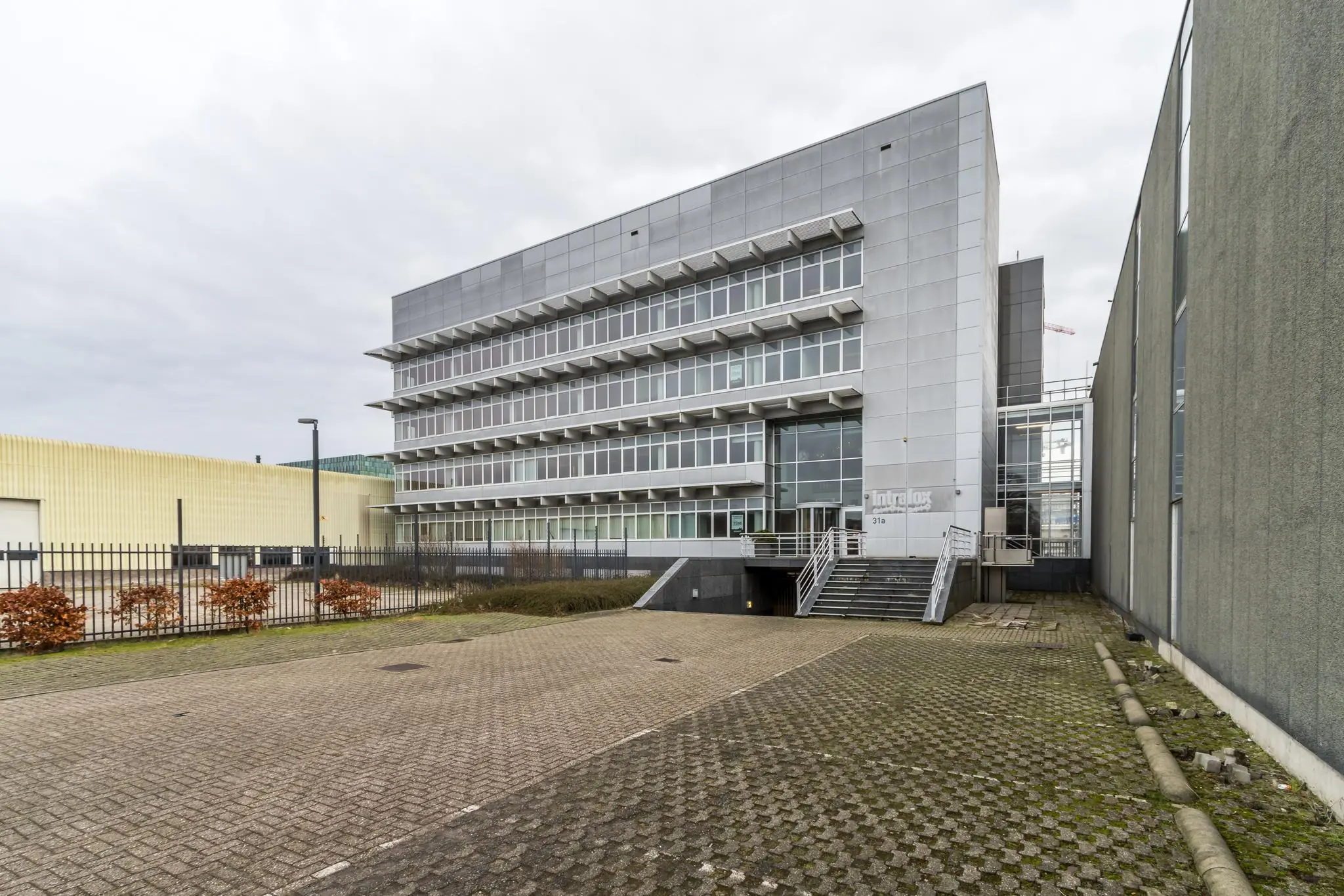 Modern kantoorpand aan de Lemelerbergweg met metalen gevelbekleding en glazen voorzijde.