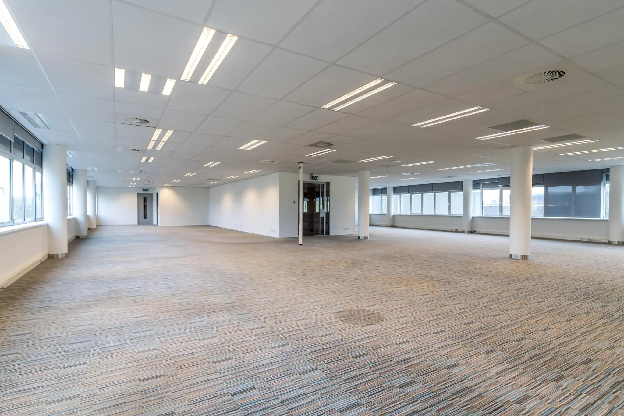 Lichte, lege kantoorruimte aan de Lemelerbergweg met grote ramen en systeemplafond.