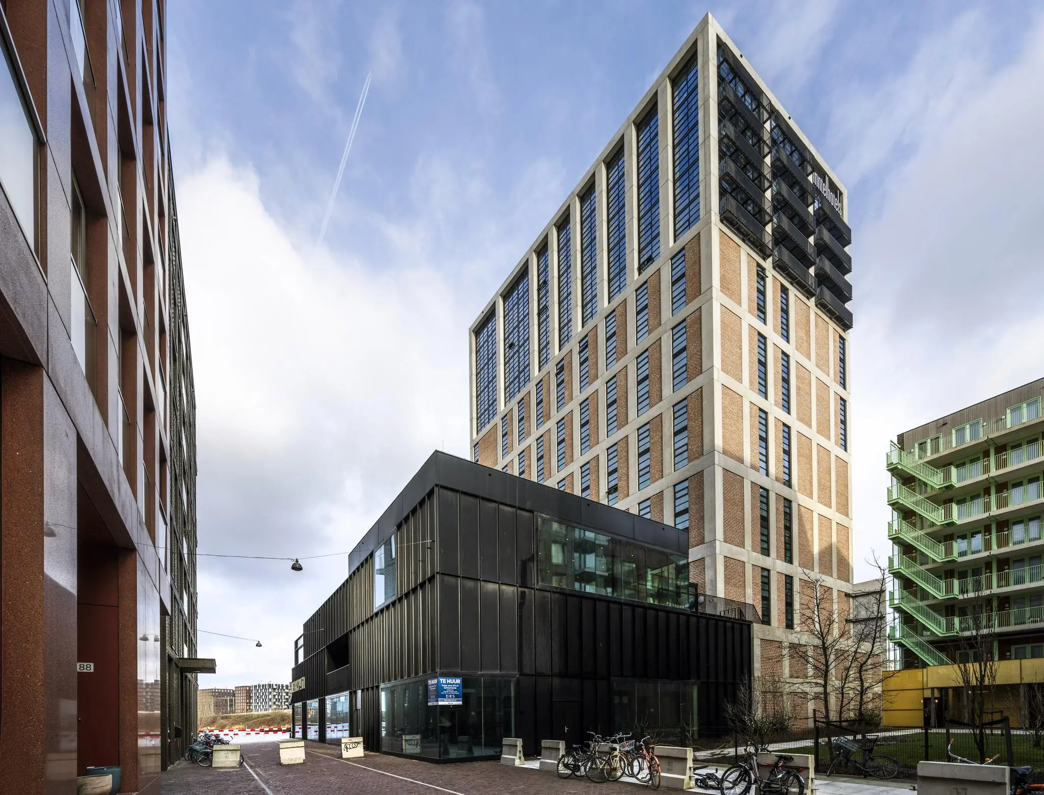 Straatbeeld van de Pieter Goosstraat met moderne hoogbouw en geparkeerde fietsen in Amsterdam.