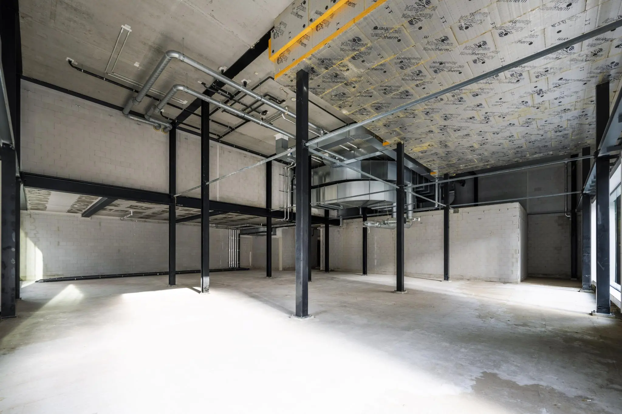 Leegstaand industrieel pand aan de Pieter Goosstraat met zicht op betonnen vloer, metalen constructie en zichtbare ventilatiebuizen.