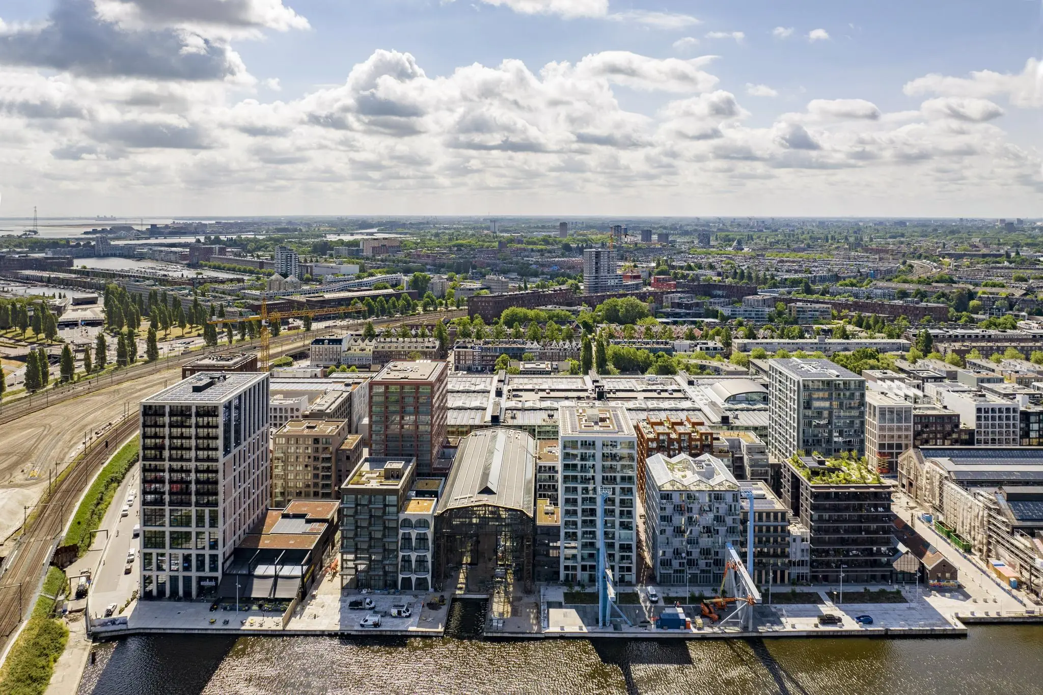 Luchtfoto van de Pieter Goosstraat in Amsterdam met moderne appartementen aan het water en het omliggende stadslandschap.