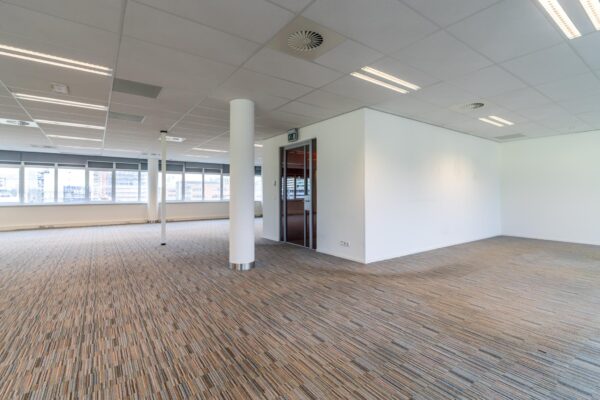 Licht en ruim kantoorinterieur aan de Lemelerbergweg met tapijtvloer, systeemplafond en grote ramen.
