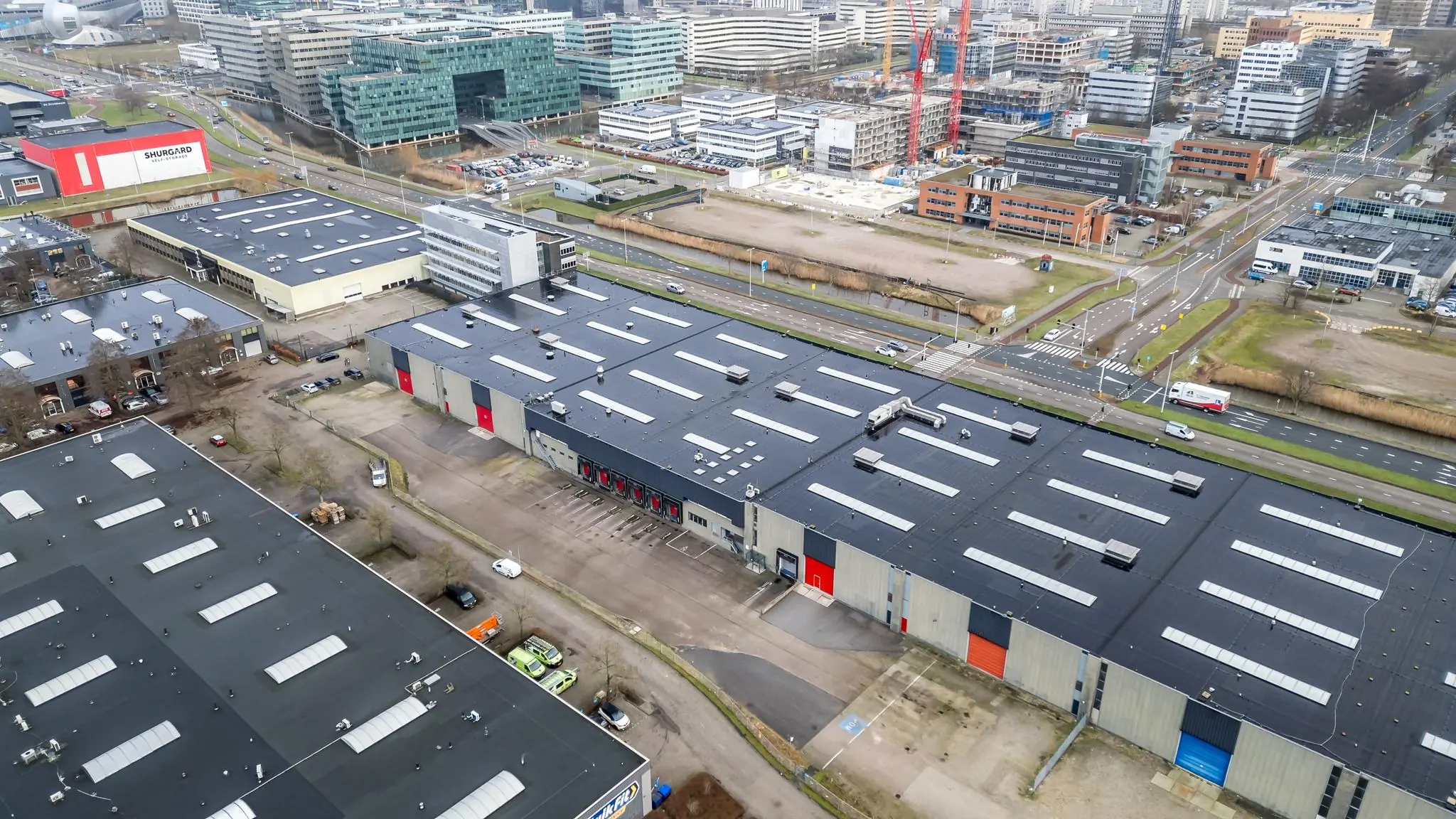 Luchtfoto van een bedrijventerrein aan de Lemelerbergweg in Amsterdam, met meerdere magazijnen en kantoren langs een drukke weg.