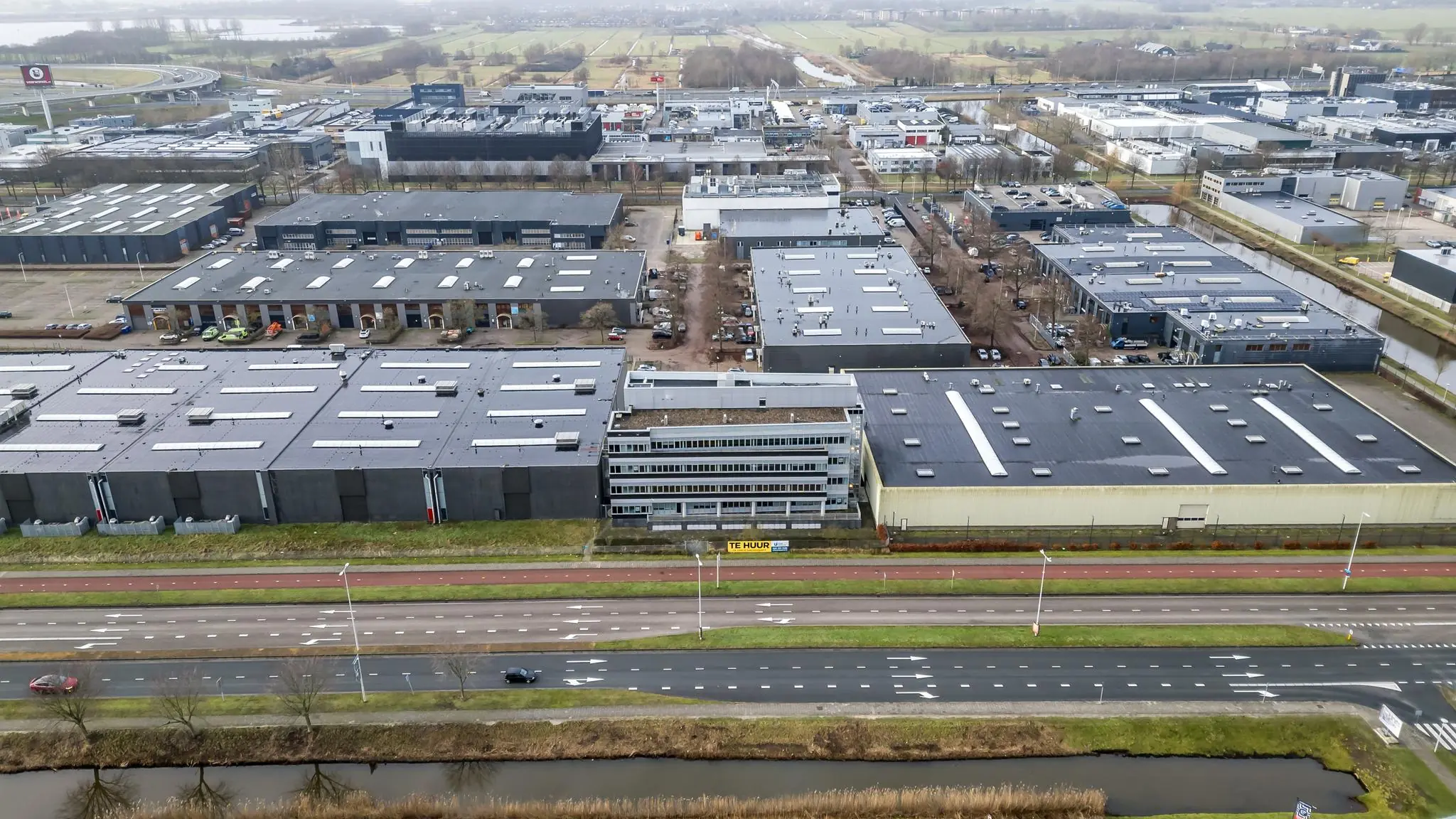 Luchtopname van een bedrijventerrein aan de Lemelerbergweg met kantoorgebouwen, loodsen en omliggende infrastructuur.