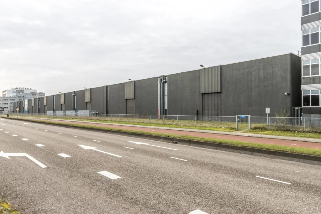 Grijze industriële loods aan de Lemelerbergweg in Amsterdam, gezien vanaf de straatzijde.