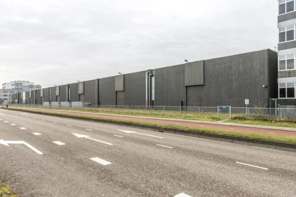 Grijze industriële loods aan de Lemelerbergweg in Amsterdam, gezien vanaf de straatzijde.