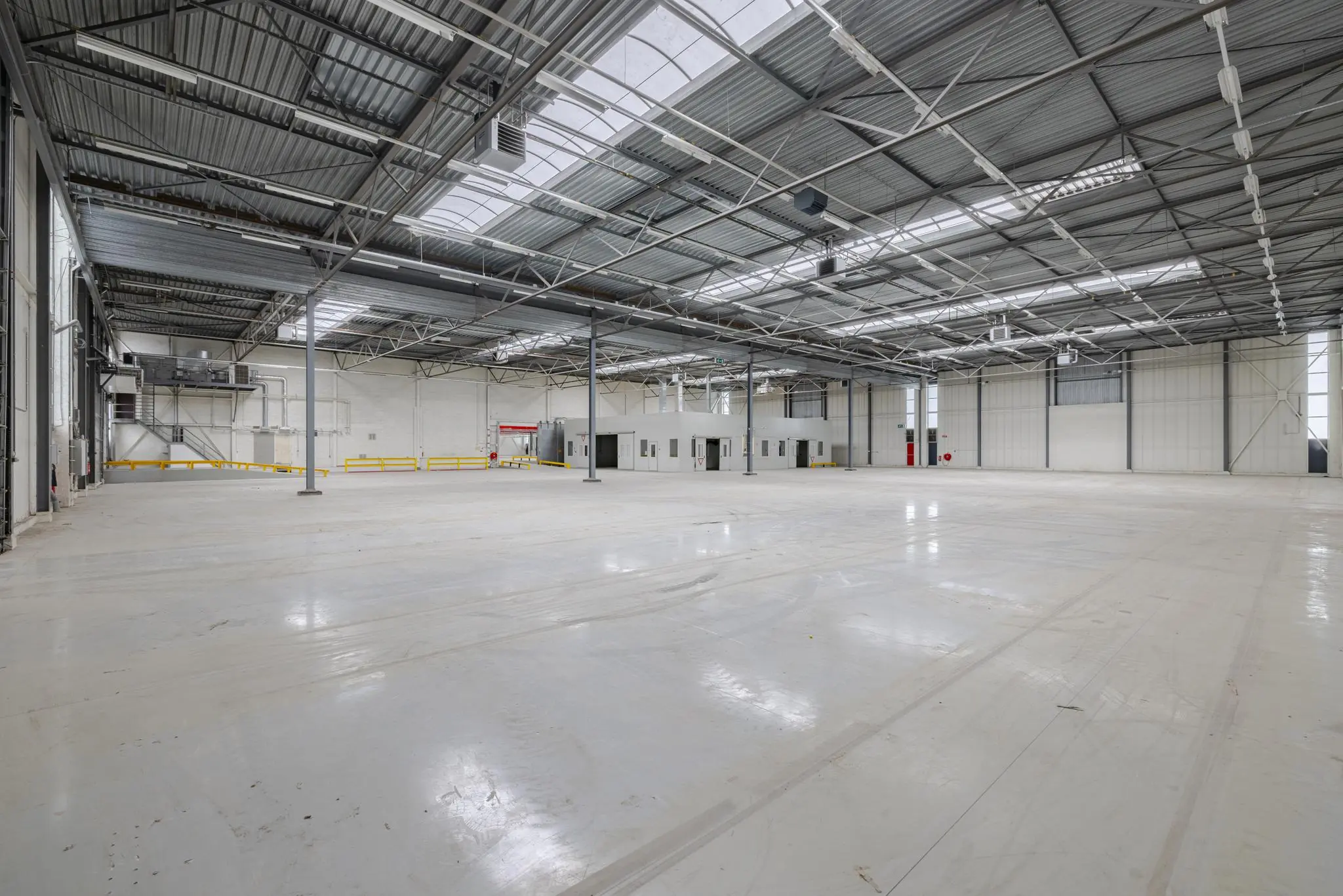 Ruime, lege bedrijfshal aan de Lemelerbergweg met betonnen vloer en metalen dakconstructie.