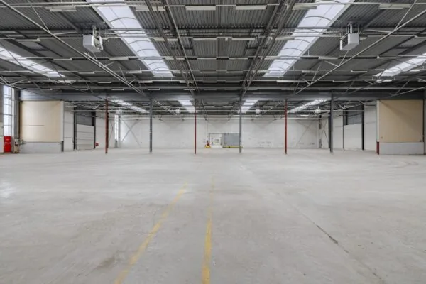 Lege industriële loods aan de Lemelerbergweg met betonnen vloer, stalen dakconstructie en grote witte roldeuren.