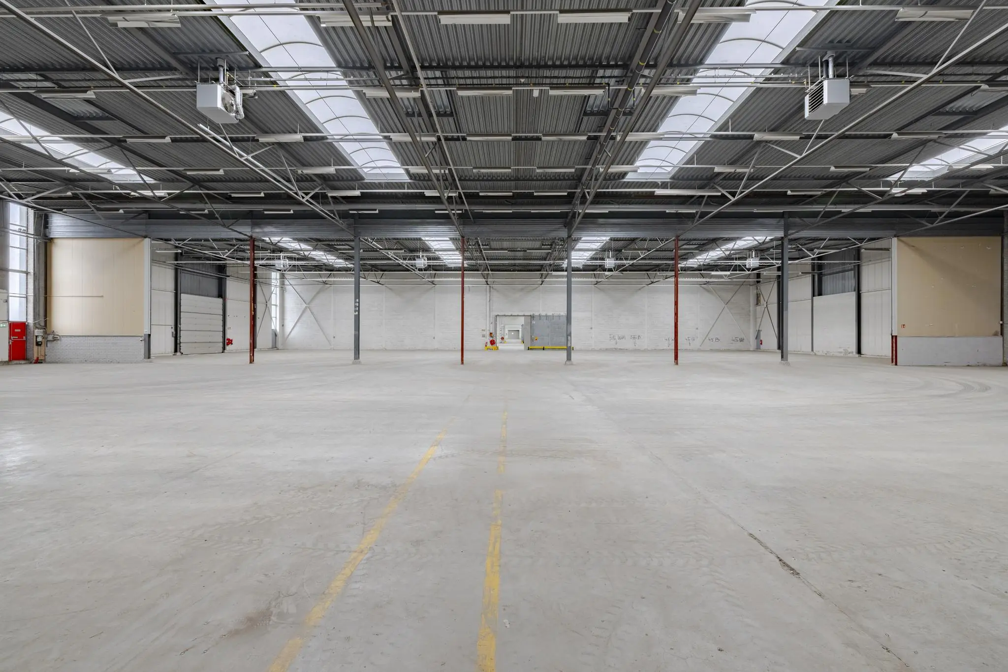 Lege industriële loods aan de Lemelerbergweg met betonnen vloer, stalen dakconstructie en grote witte roldeuren.