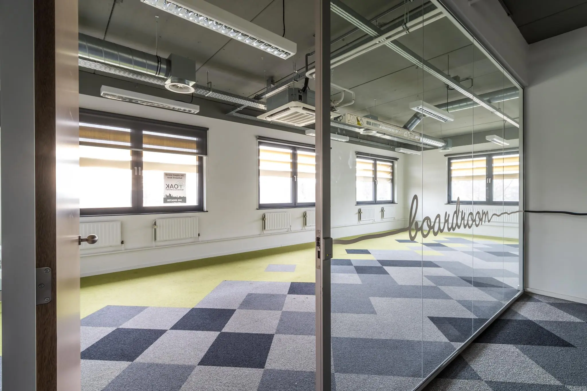 Moderne, lichte vergaderruimte met glazen wand waarop "boardroom" staat, gelegen aan de Laarderhoogtweg.