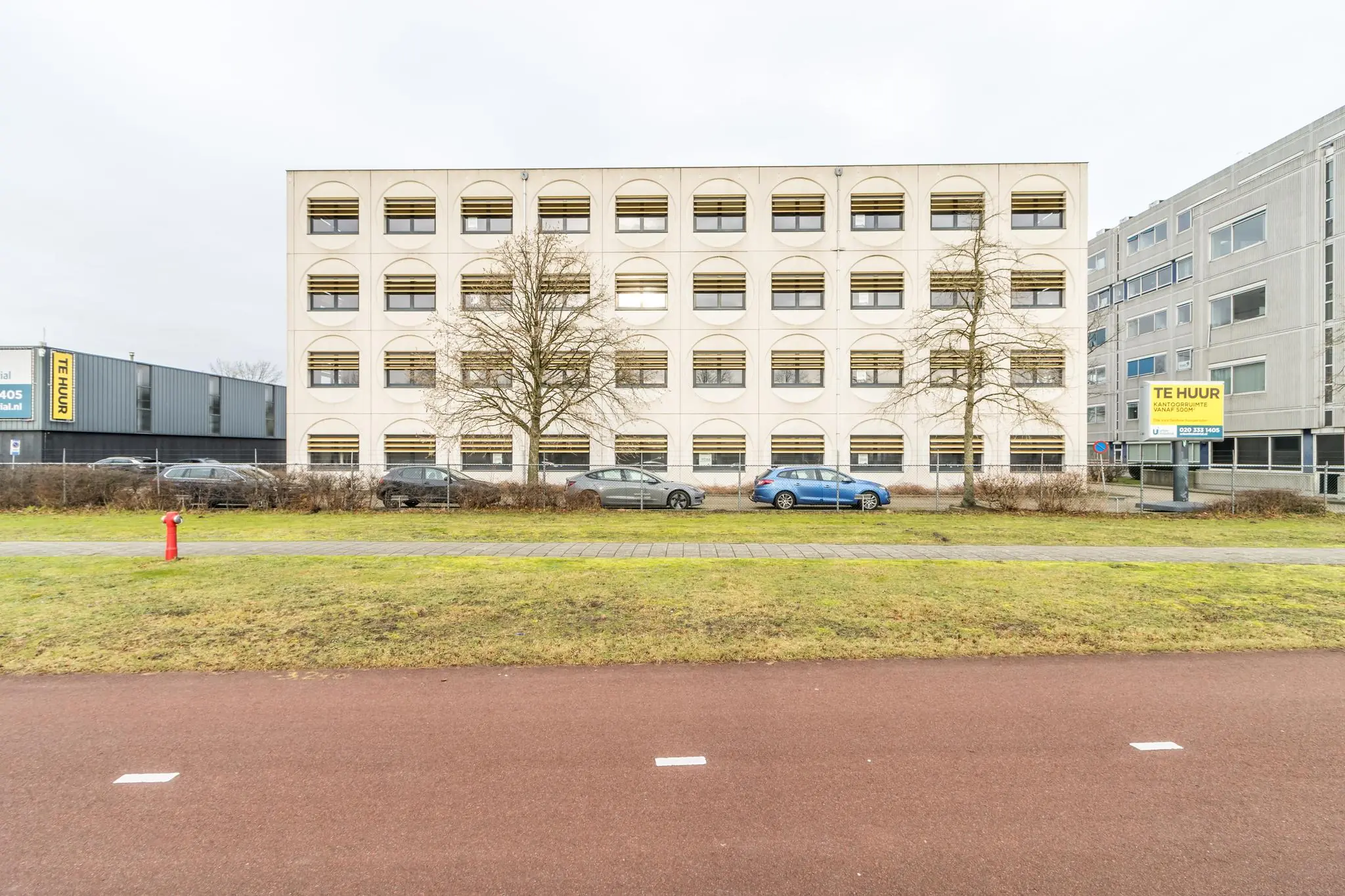 Kantoorpand aan de Laarderhoogtweg met parkeerplaatsen en 'Te Huur' borden zichtbaar aan de gevel.