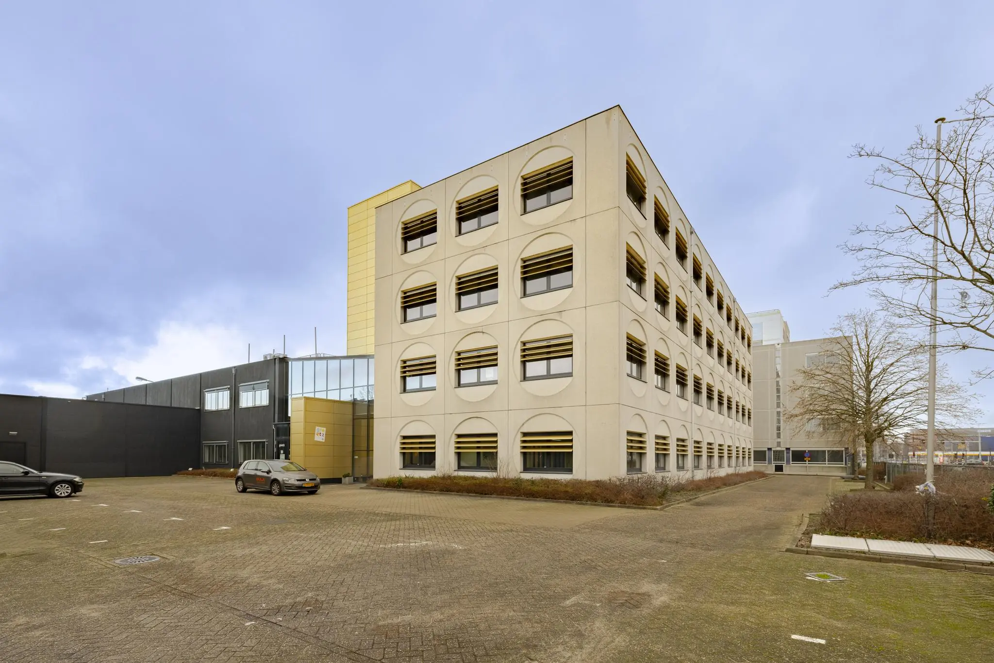 Kantoorgebouw aan de Laarderhoogtweg met opvallende ronde raamkaders en een lege parkeerplaats op de voorgrond.