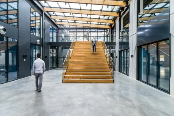 Moderne lichte entreehal met een brede houten trap in een kantoorgebouw aan de Laarderhoogtweg.