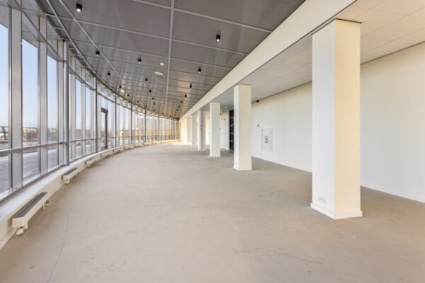 Licht en modern kantoorpand aan de Curieweg met grote gebogen glazen gevel en open ruimte.