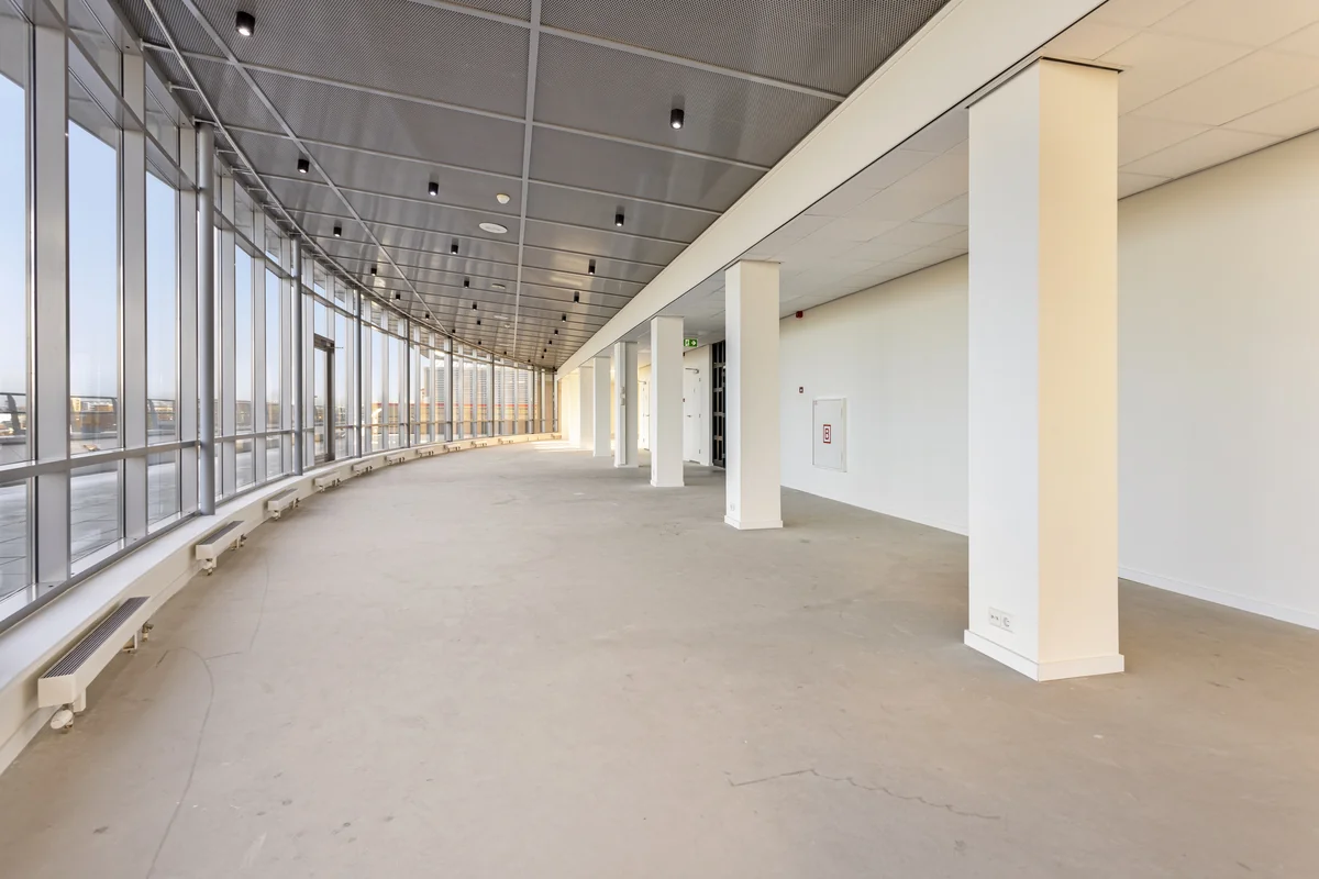 Licht en modern kantoorpand aan de Curieweg met grote gebogen glazen gevel en open ruimte.