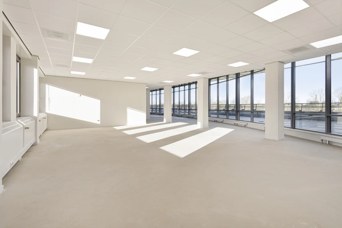 Licht en ruim leeg kantoorpand aan de Curieweg met grote ramen en systeemplafond.