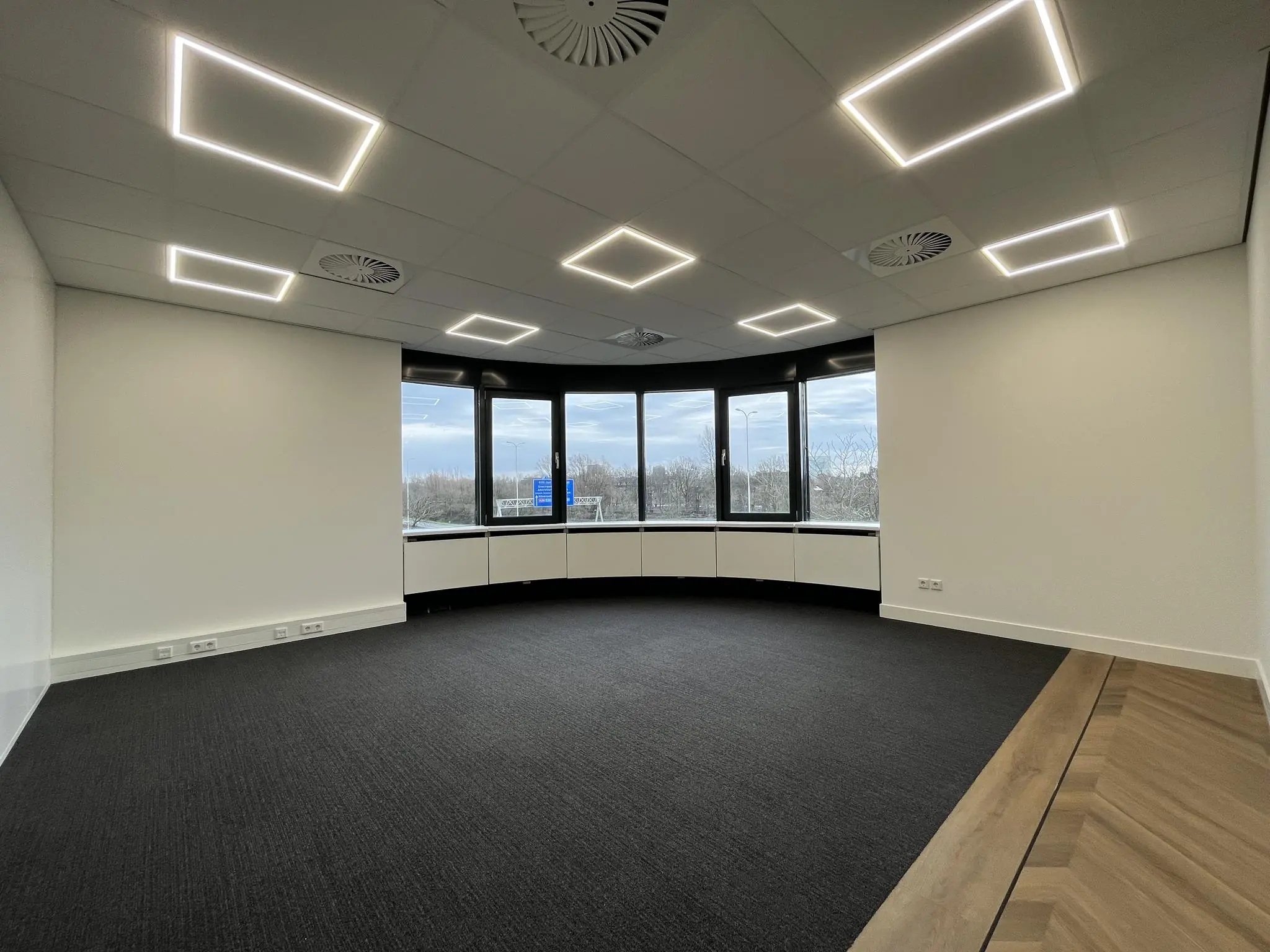 Leeg en modern kantoorruimte aan de Euclideslaan met grote ramen en vierkante plafondverlichting.