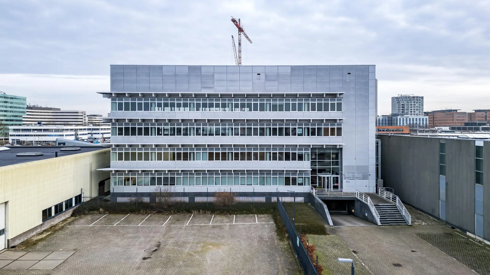 Kantoorgebouw aan de Lemelerbergweg met glazen gevel en aangrenzende parkeerplaats in Amsterdam Zuidoost.