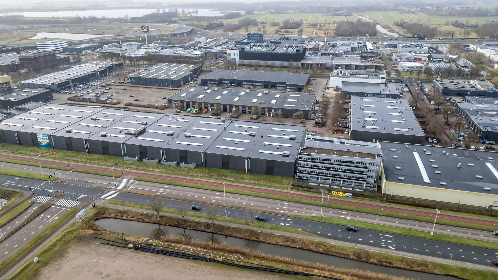 Luchtfoto van een bedrijventerrein aan de Lemelerbergweg in Amsterdam met meerdere bedrijfsgebouwen en omliggende wegen.
