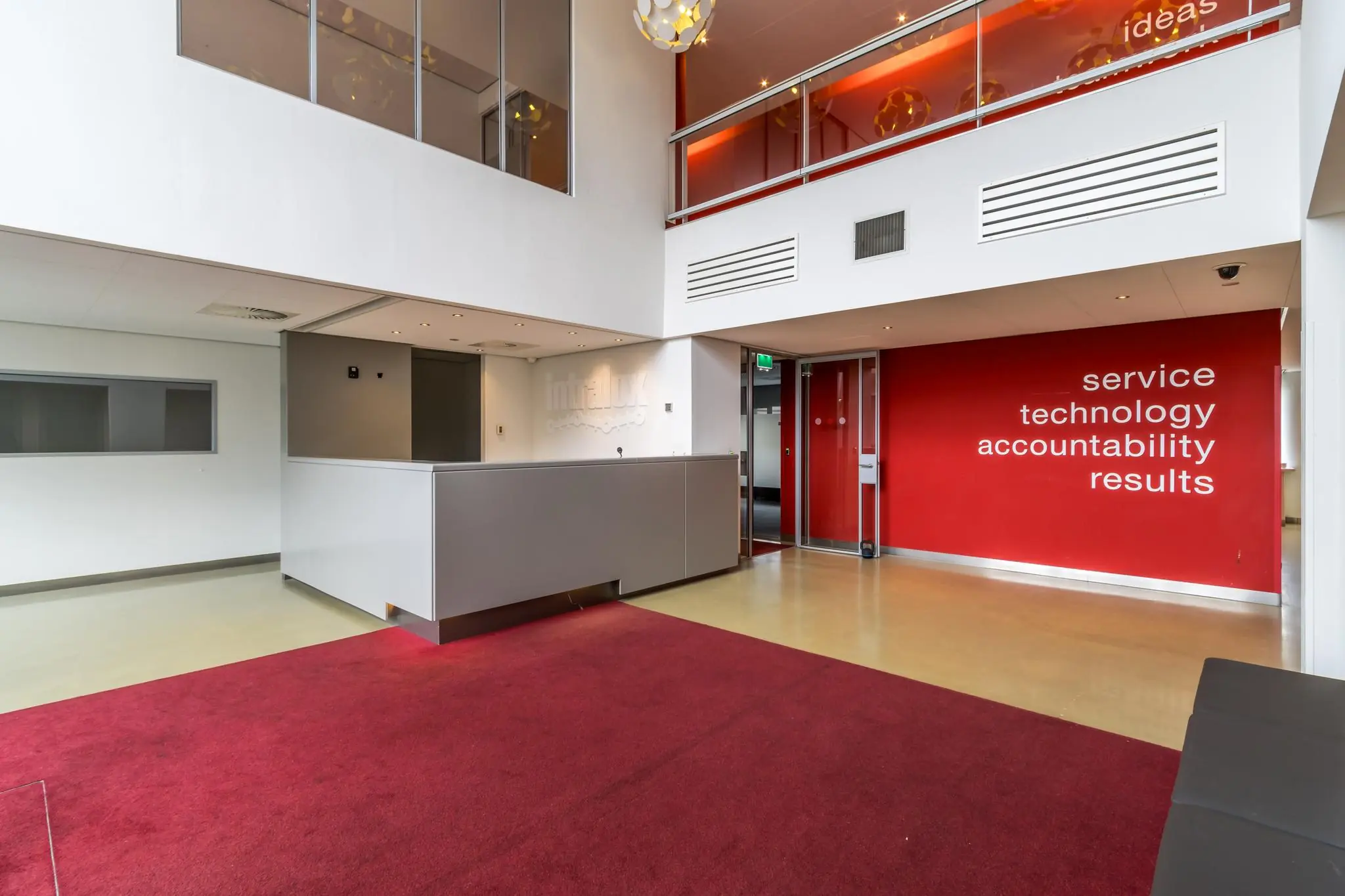 Moderne kantoorentree aan de Lemelerbergweg met rode accenten, een balie en bedrijfswaarden op de muur.