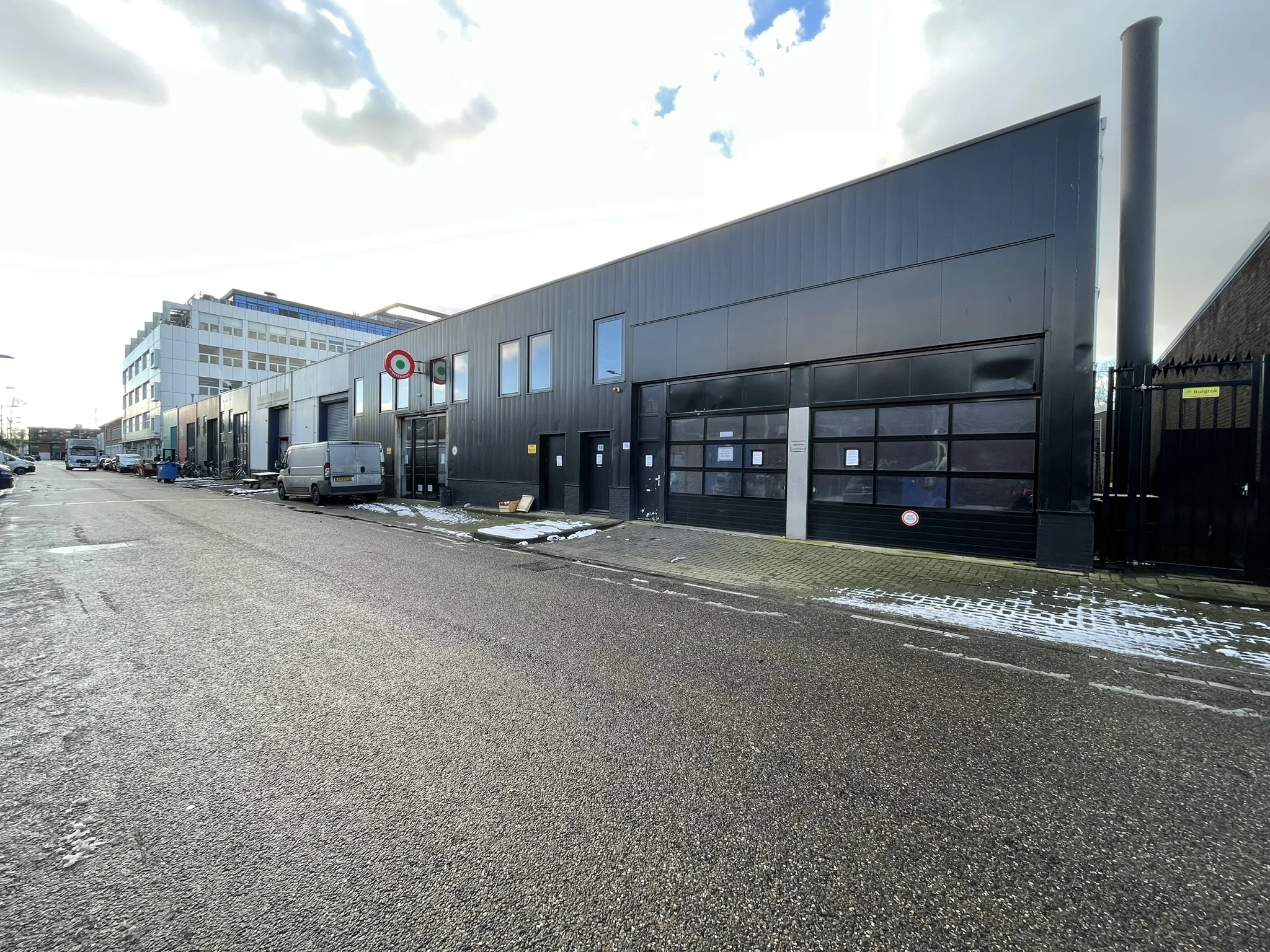 Bedrijfsgebouwen aan de Pilotenstraat met geparkeerde bus en lichte sneeuw op de stoep.