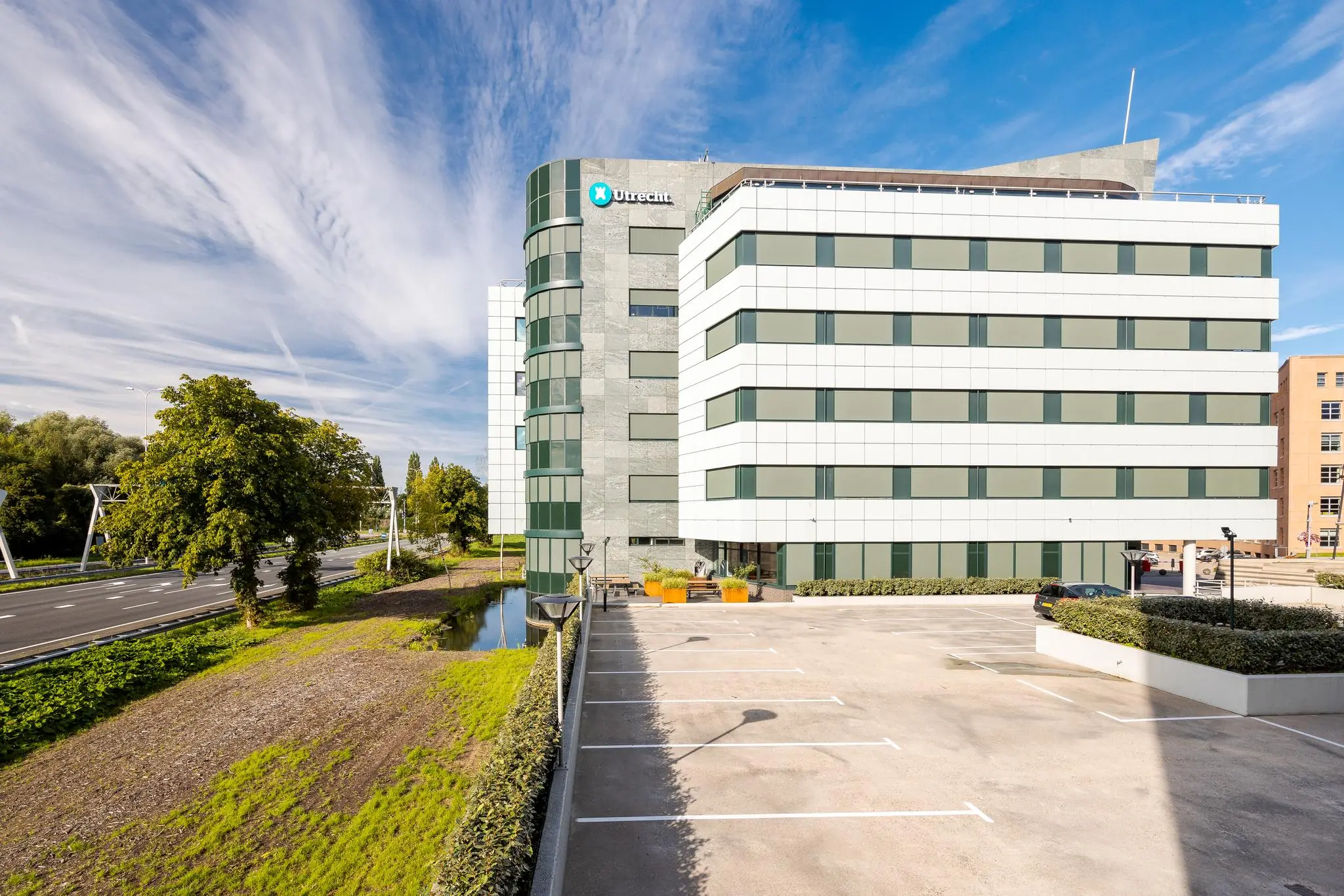 Kantoorgebouw aan de Euclideslaan in Utrecht met parkeerterrein op de voorgrond en een heldere blauwe lucht.