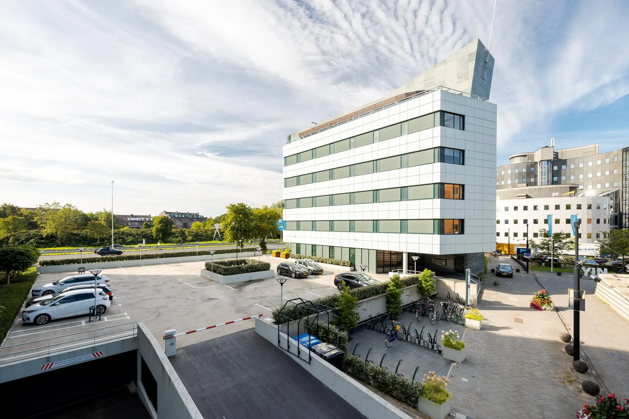 Modern kantoorgebouw aan de Euclideslaan in Utrecht met parkeerplaatsen, fietsenstalling en omliggende kantoren.