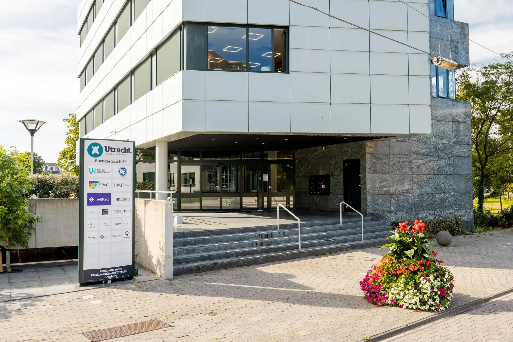 Ingang van een modern kantoorgebouw aan de Euclideslaan in Utrecht met bedrijfsbord en bloembak op de voorgrond.