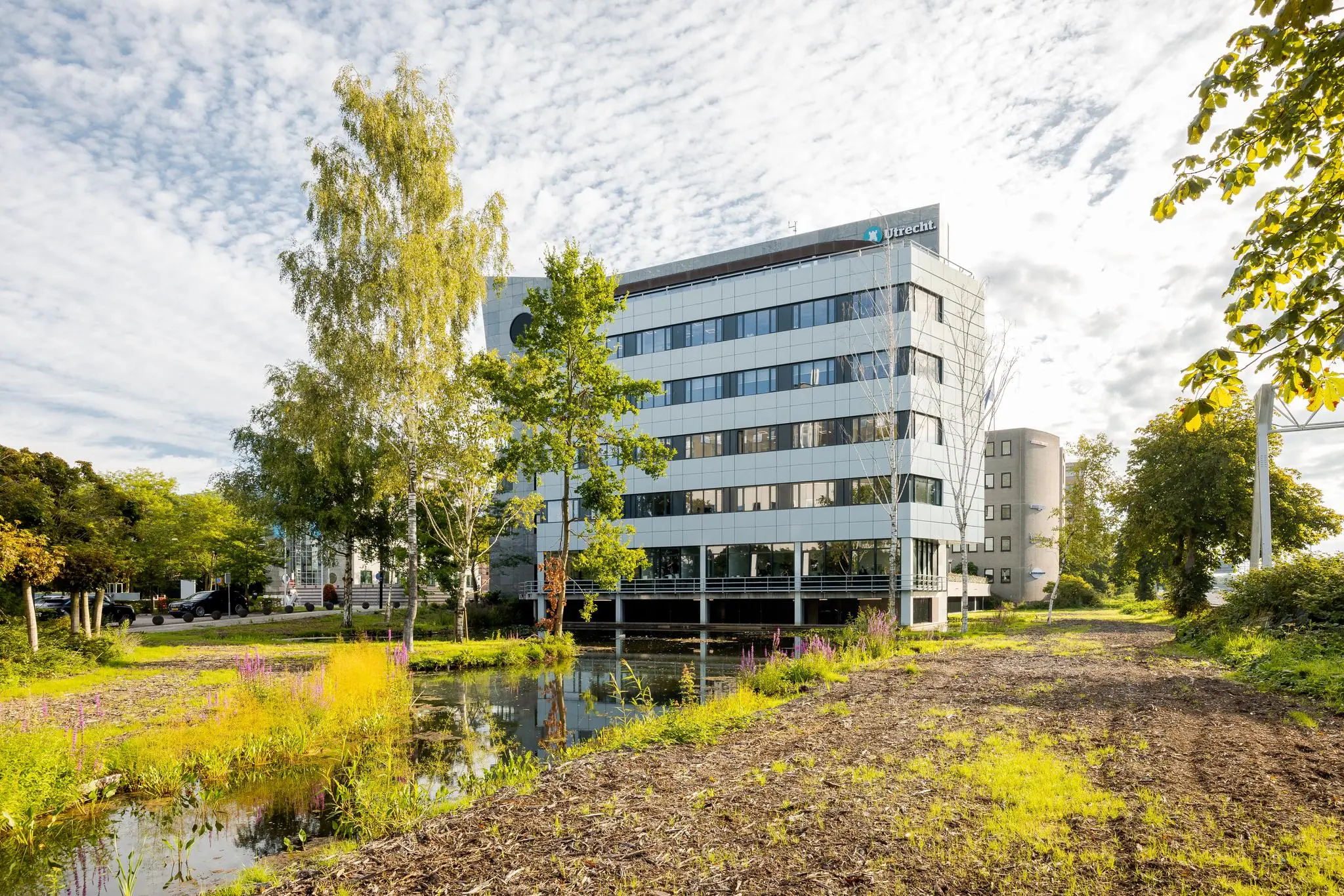 Kantoorgebouw aan de Euclideslaan in Utrecht met vijver en groene omgeving op de voorgrond.