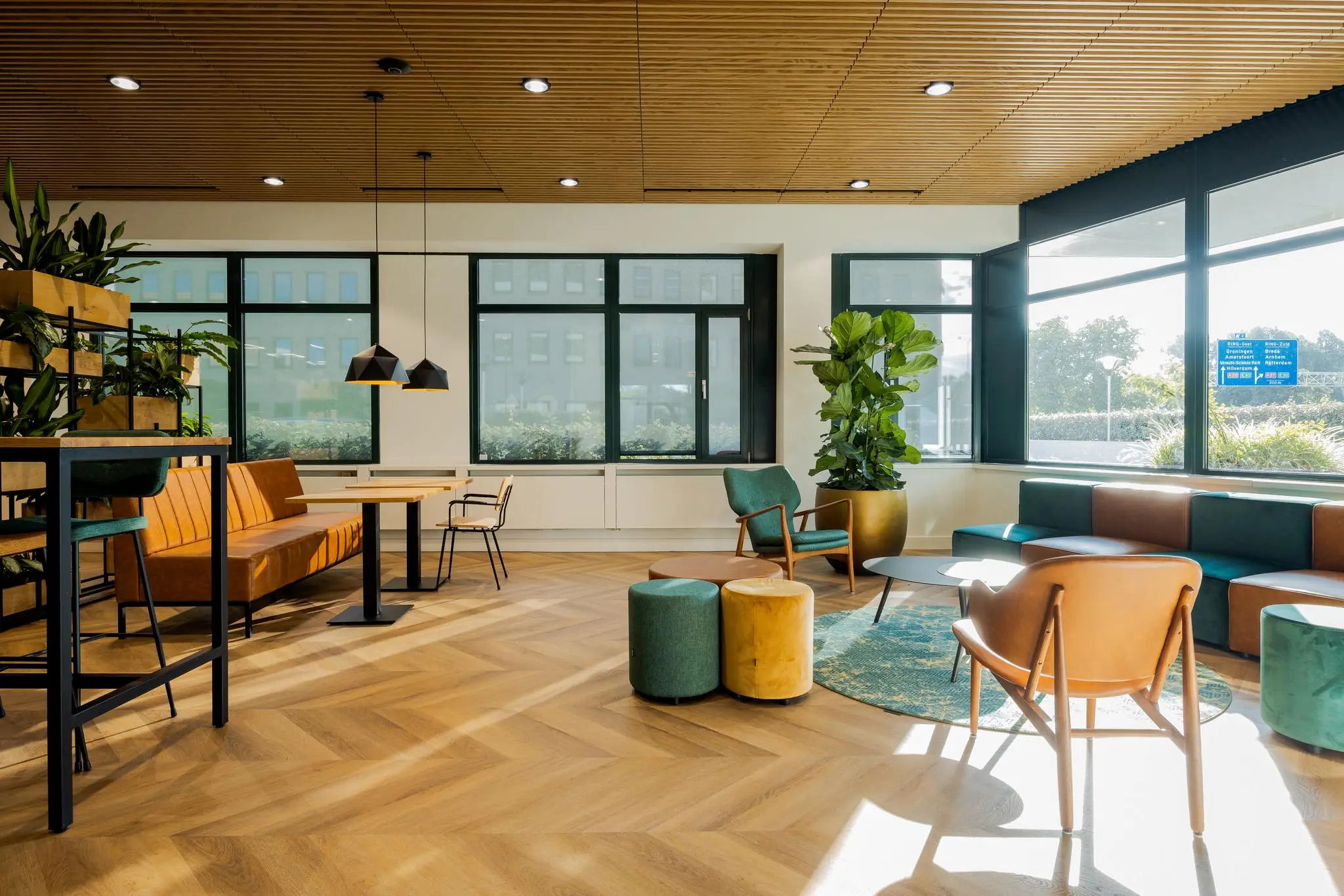 Moderne, zonnige wachtruimte of lounge aan de Euclideslaan met houten vloer, designmeubels en veel groen.