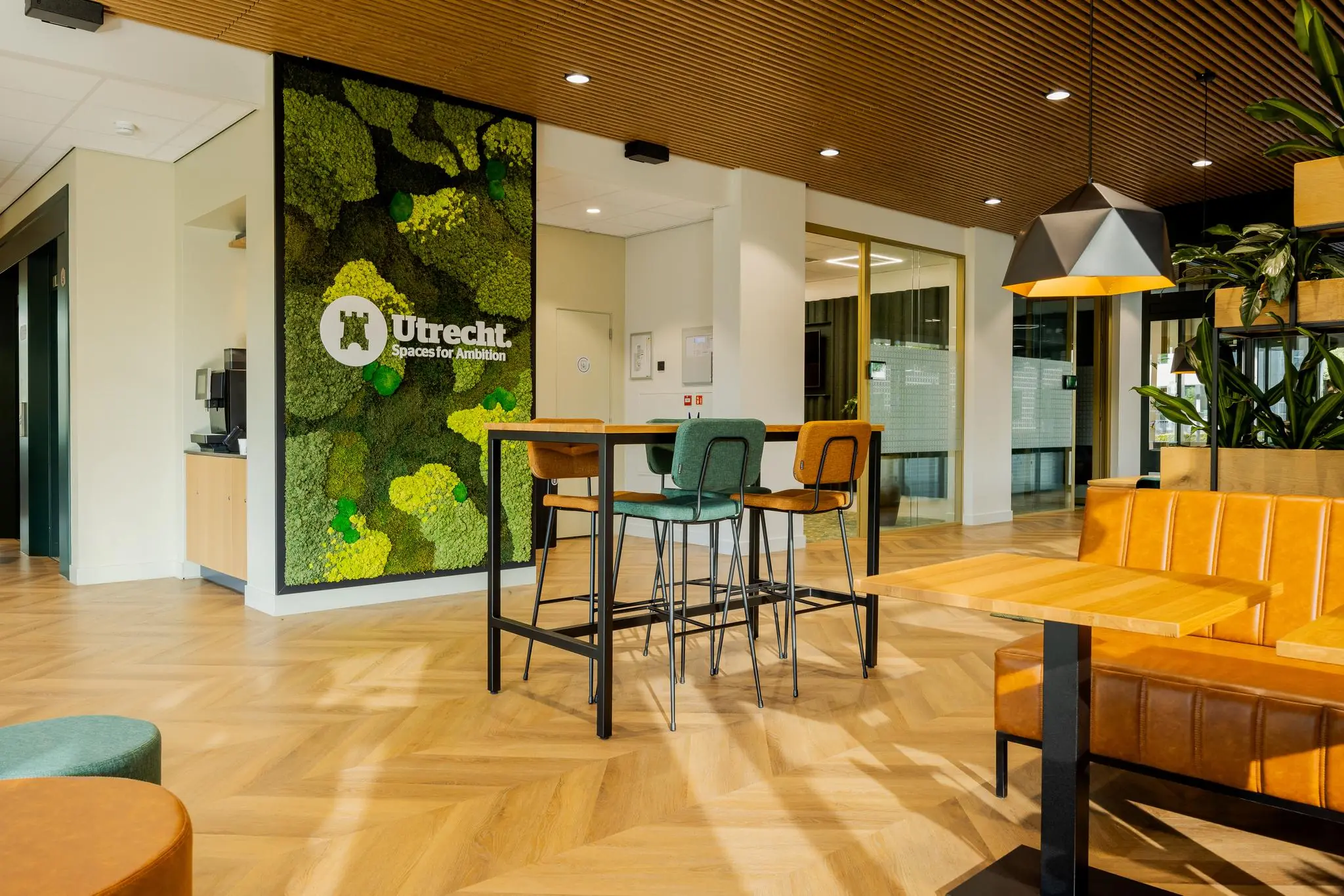 Moderne kantoorruimte aan de Euclideslaan in Utrecht met houten vloer, groen moswand en kleurrijk meubilair.
