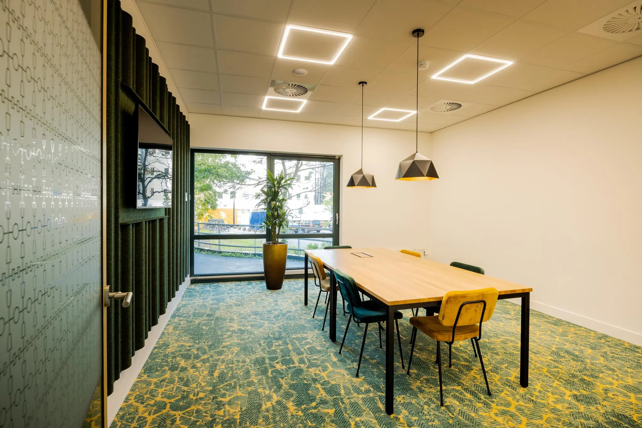 Vergaderruimte aan de Euclideslaan met lange houten tafel, designverlichting en groot raam met uitzicht naar buiten.