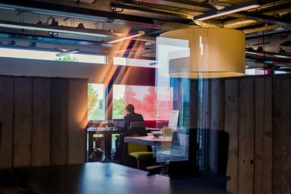 Man werkt op laptop in modern kantoor aan de Orteliuslaan met kleurrijke lichtreflecties op het raam.