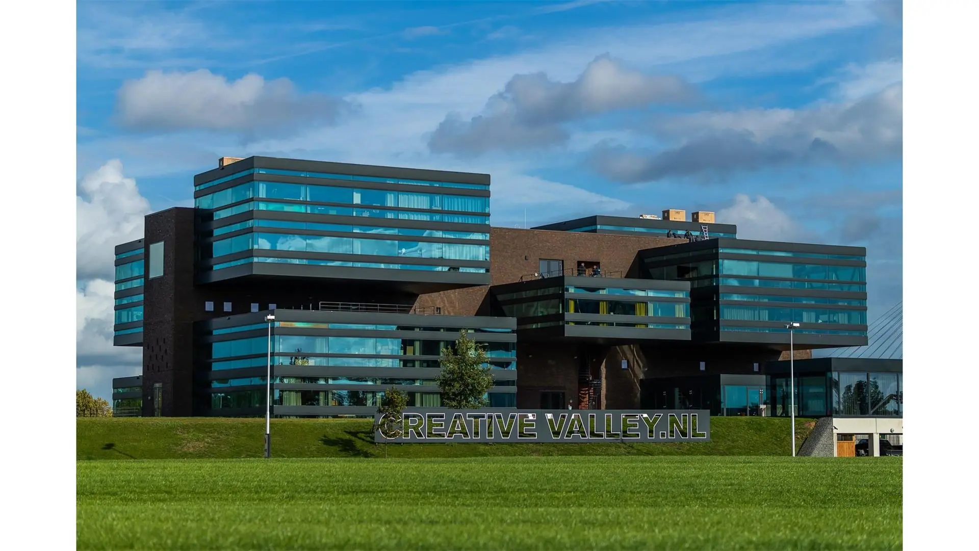 Modern kantoorgebouw Creative Valley aan de Orteliuslaan met opvallende glazen gevel en groene voorgrond.