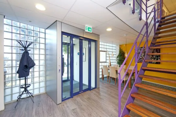Moderne entreehal aan de Zuiderweg met een lift, paarse trap, glazen bouwstenen en een vergaderruimte.