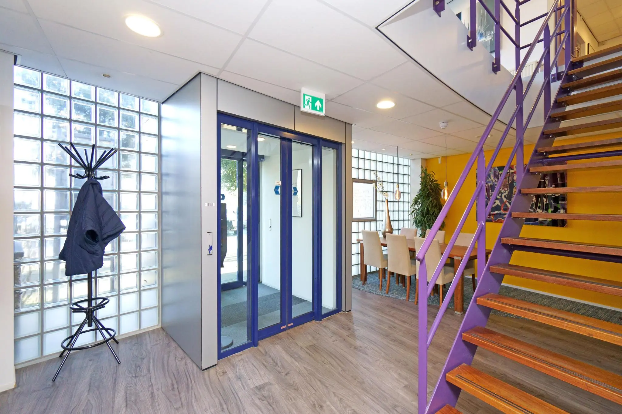 Moderne entreehal aan de Zuiderweg met een lift, paarse trap, glazen bouwstenen en een vergaderruimte.